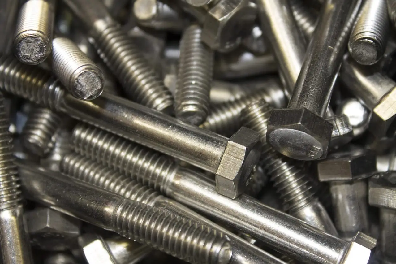 A single galvanised anchor bolt photographed against a dark metal surface.