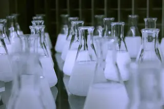 Glass laboratory flasks and measuring cylinders used for material testing.