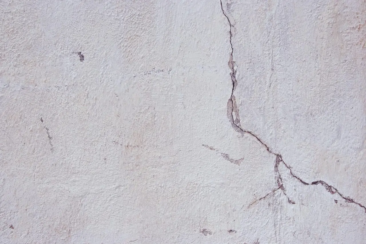 A long branching crack running down a rendered masonry wall.